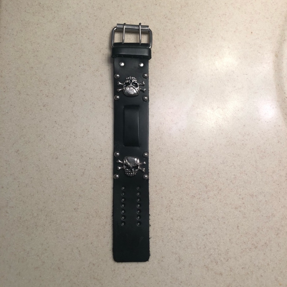 Black leather wristband with skull details. Measures 9 1/2” x 1 1/2”